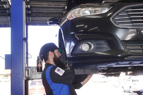 General Maintenance Services in Escondido, CA with John's Auto Pros; image of ASE certified master tech performing brake maintenance on car on lift in shop bay