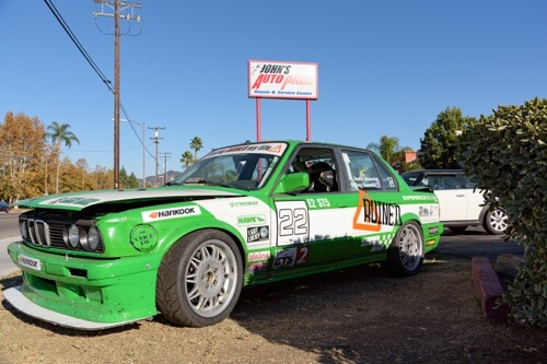 Race Car service and repair in Escondido, CA image of lime green and white BMW race car parked outside of John's Auto Pros 