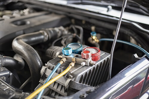 Auto Air Conditioning Repair | John's Auto Pros in Escondido, CA. Image of a device for leak detection and fill refrigerant on top of a car engine.
